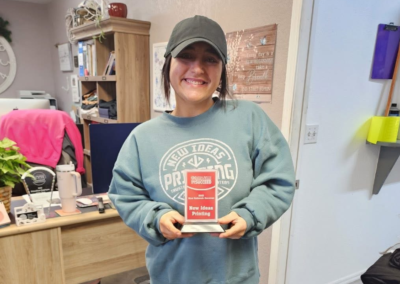 Bailey Smith with New Ideas holds an award and poses.